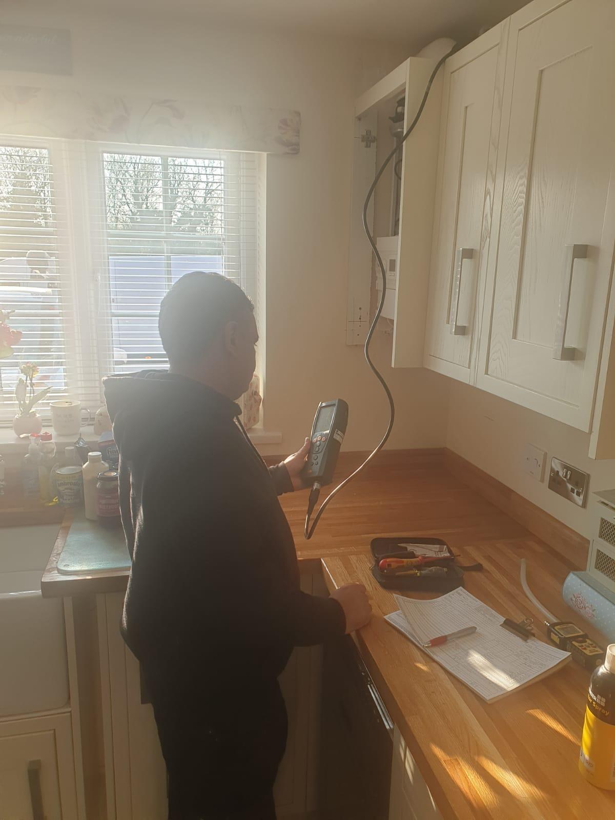 Engineer carrying out flue gas analyser test on boiler